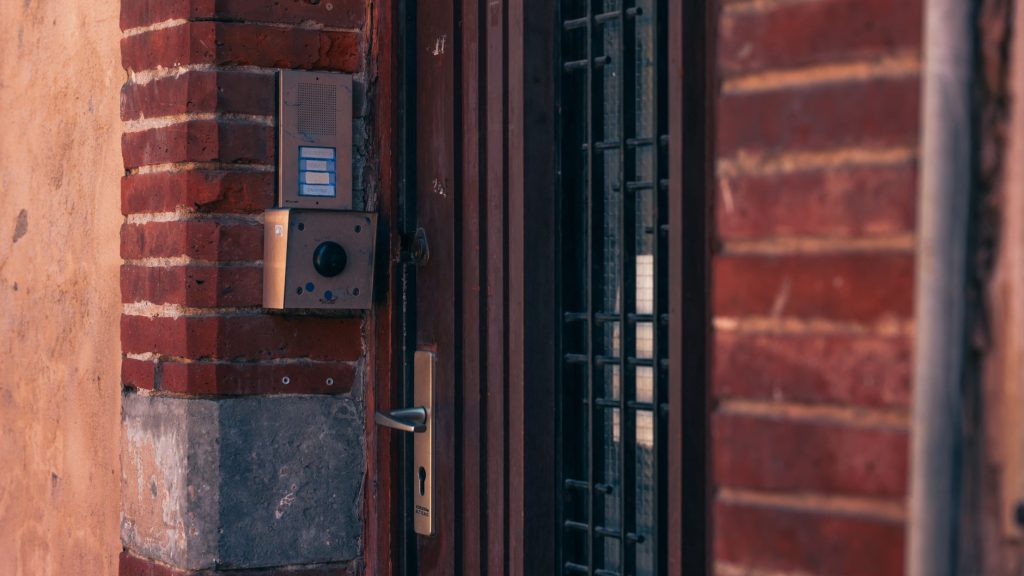 Close-up of a brick wall with a security intercom and door handles in Toulouse, France.