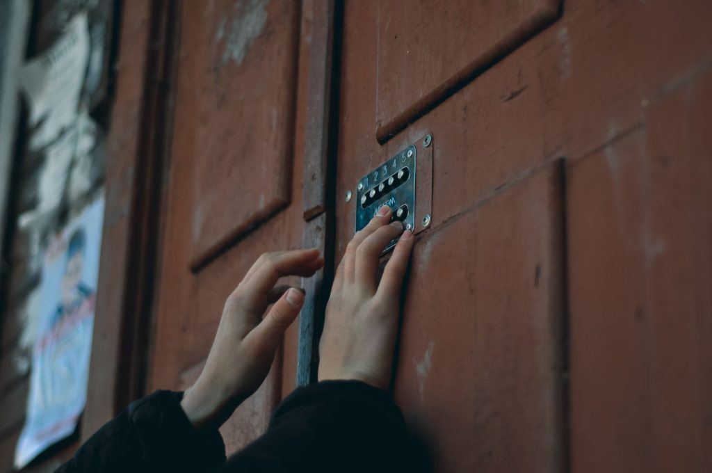 Close-up of hands pressing a keypad on a wooden door, showcasing security and access entry.