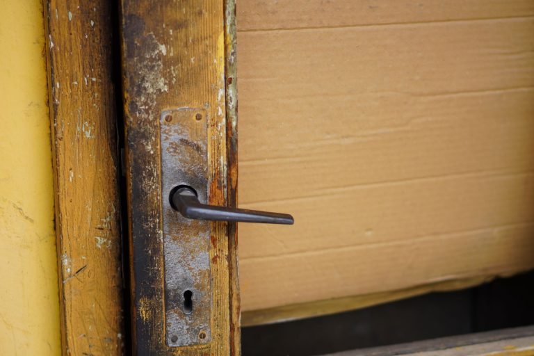 Close-up of a weathered wooden door with a vintage metal handle, showing rustic charm.